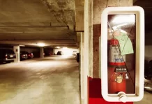 Jak wybrać odpowiednią gaśnicę do domu i samochodu Gaśnica w szafce na filarze podziemnego parkingu z samochodami.