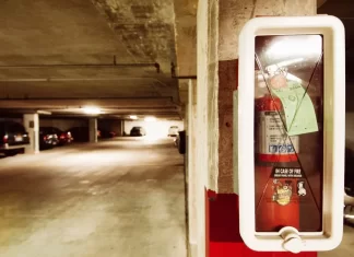 Jak wybrać odpowiednią gaśnicę do domu i samochodu Gaśnica w szafce na filarze podziemnego parkingu z samochodami.